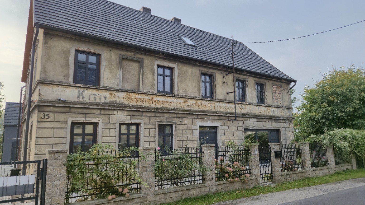 Dom nr 35 w Sieniawie Żarskiej z częściowo zatartym napisem dawnego sklepu na elewacji