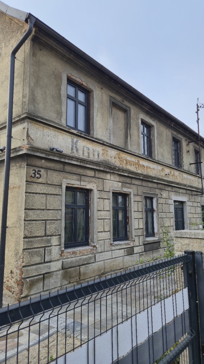 Zbliżenie częściowo zatartego szyldu na elewacji domu nr 35 w Sieniawie Żarskiej
